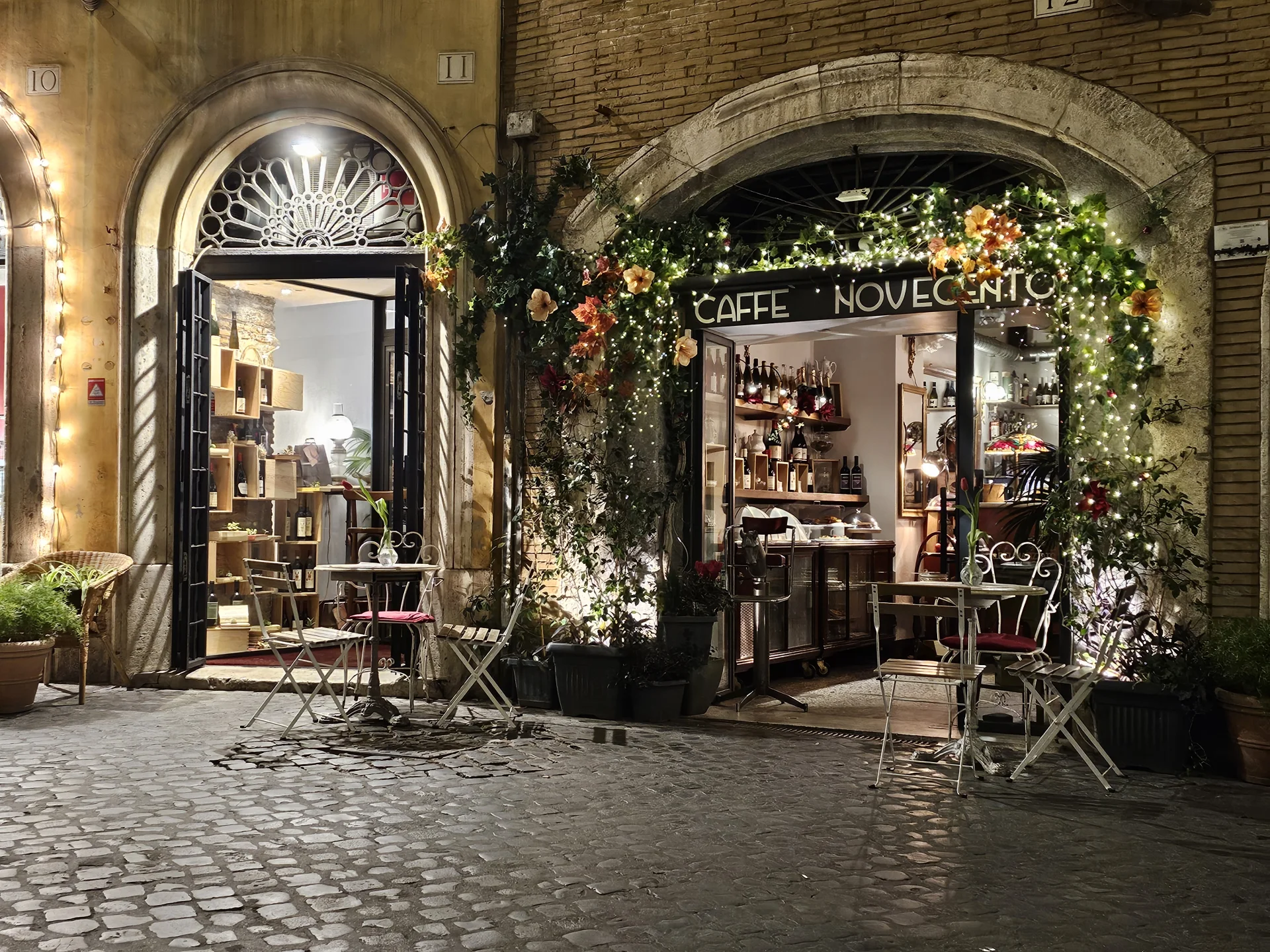 Esterno del Caffè Novecento di notte – via del Governo Vecchio, Roma, con luci calde e fiori all’ingresso