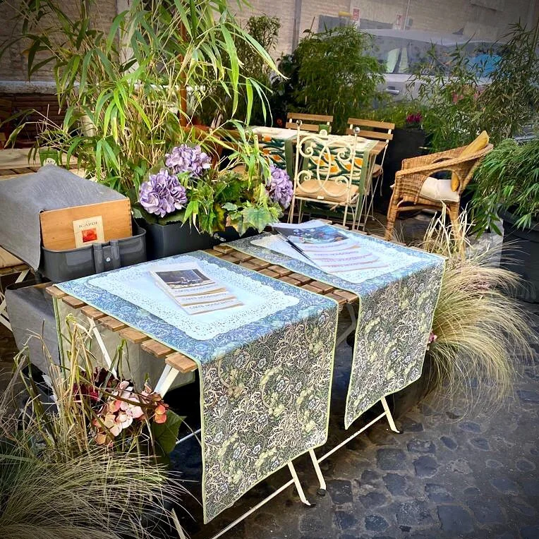 Tavolini esterni del Caffè Novecento con tovaglie floreali e ortensie – bistrot Roma